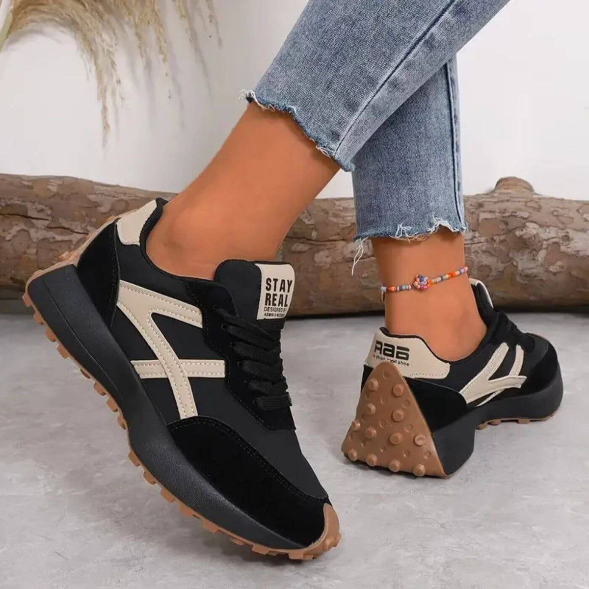 Sorte damesneakers med beige detaljer og brun gummisål, set fra siden